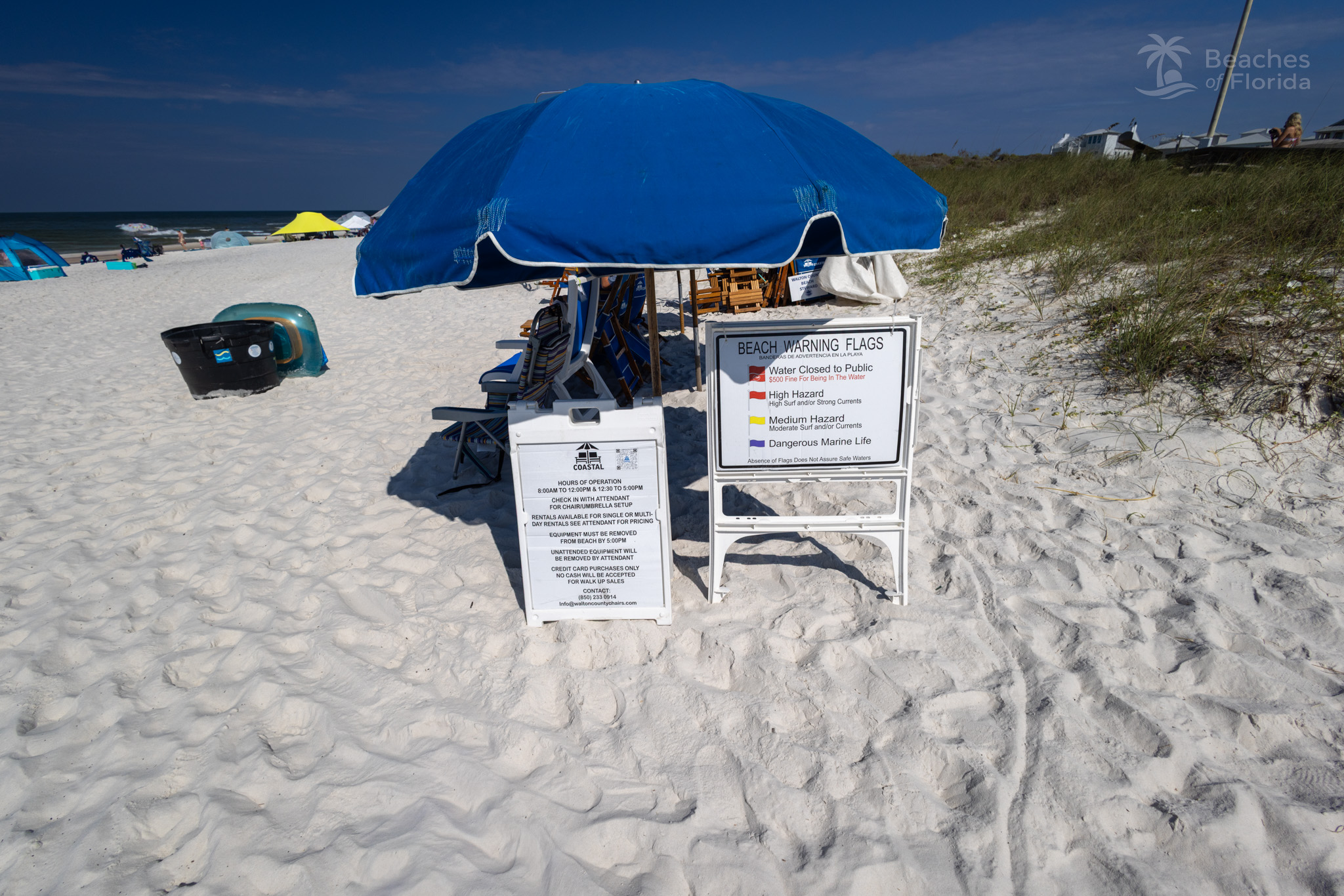 Beach chair and umbrella rental station with warning flags at Inlet Beach