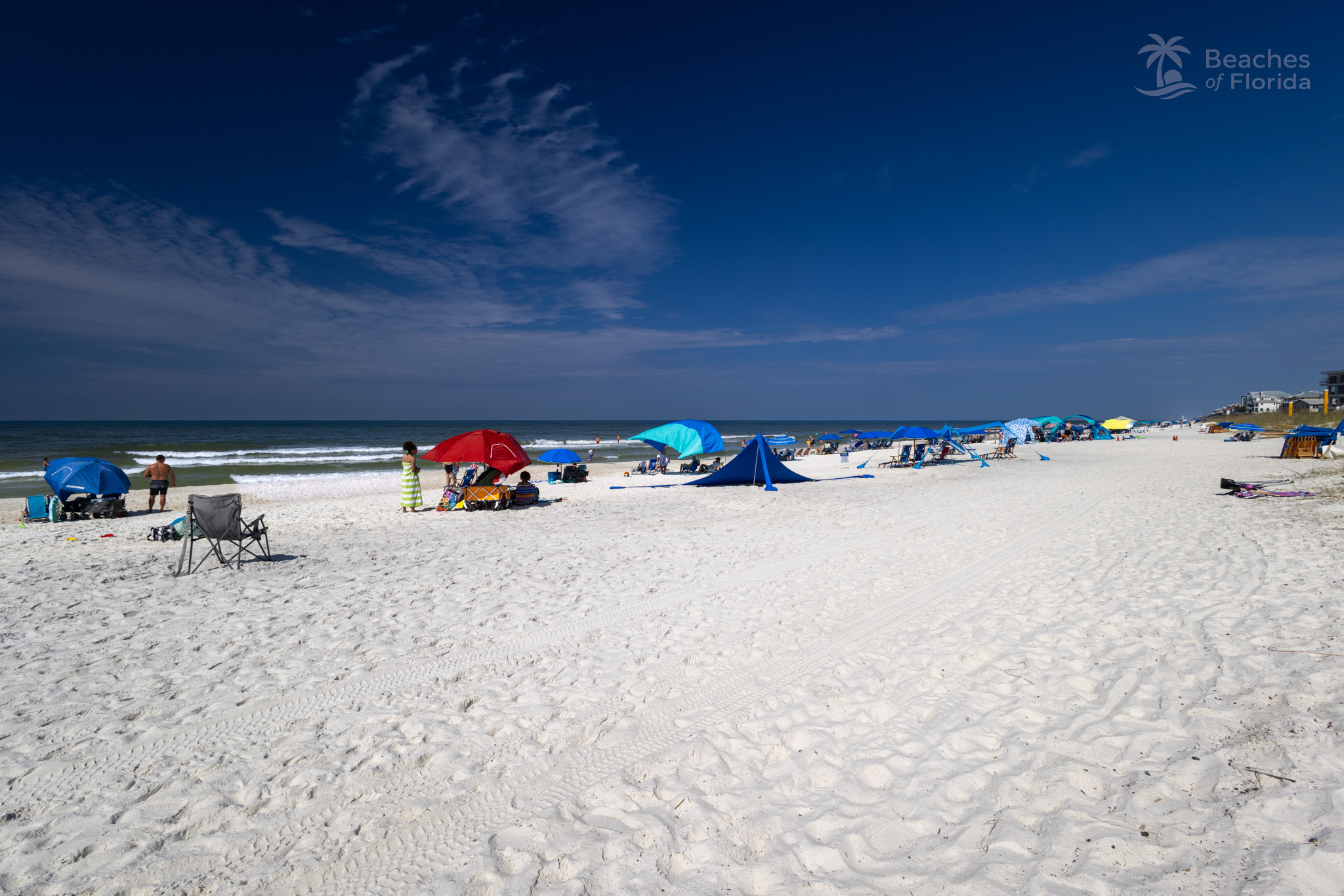 Wide view of Inlet Beach shoreline with families enjoying the sand