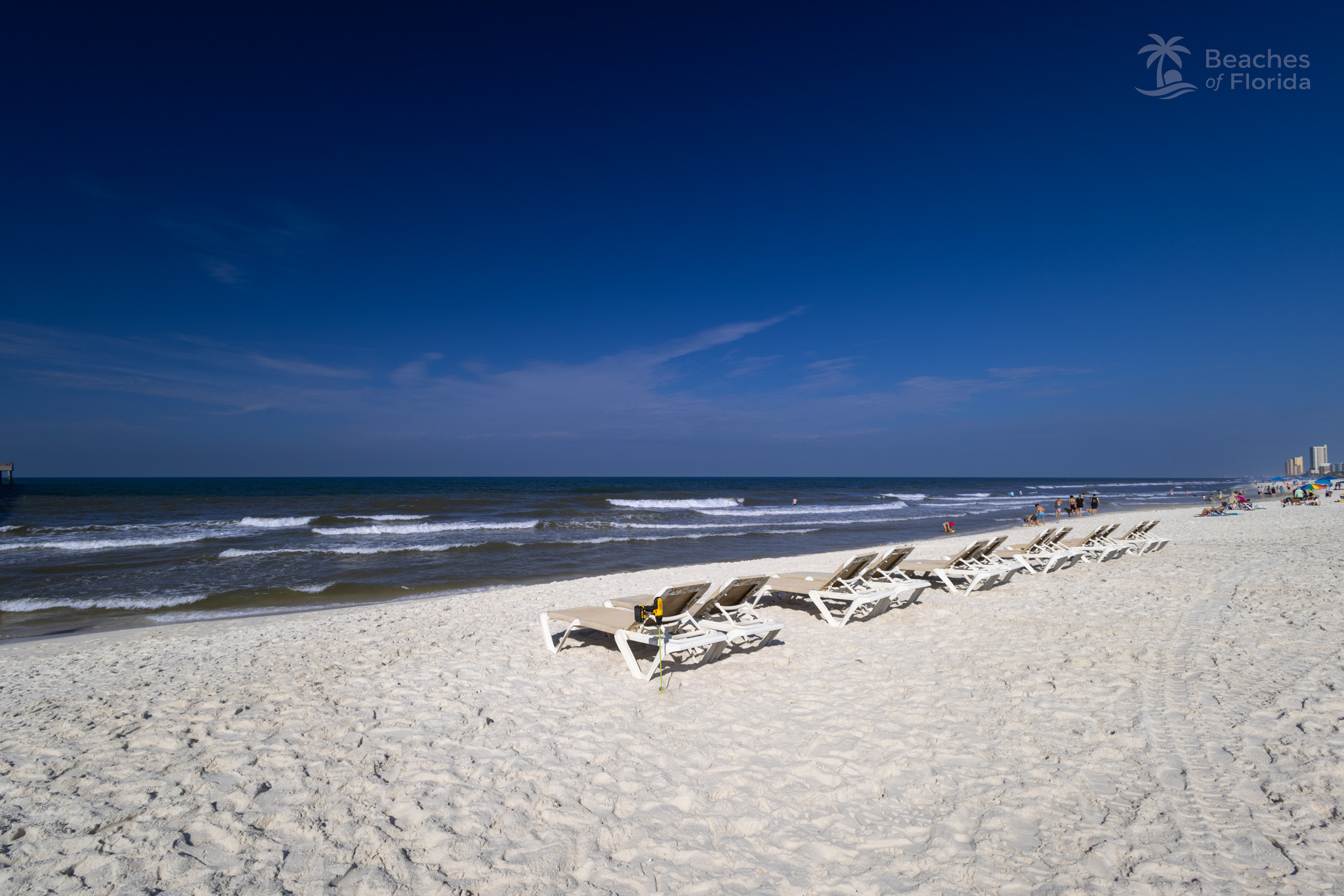 Lounge chairs lined up along the shoreline at Panama City Beach